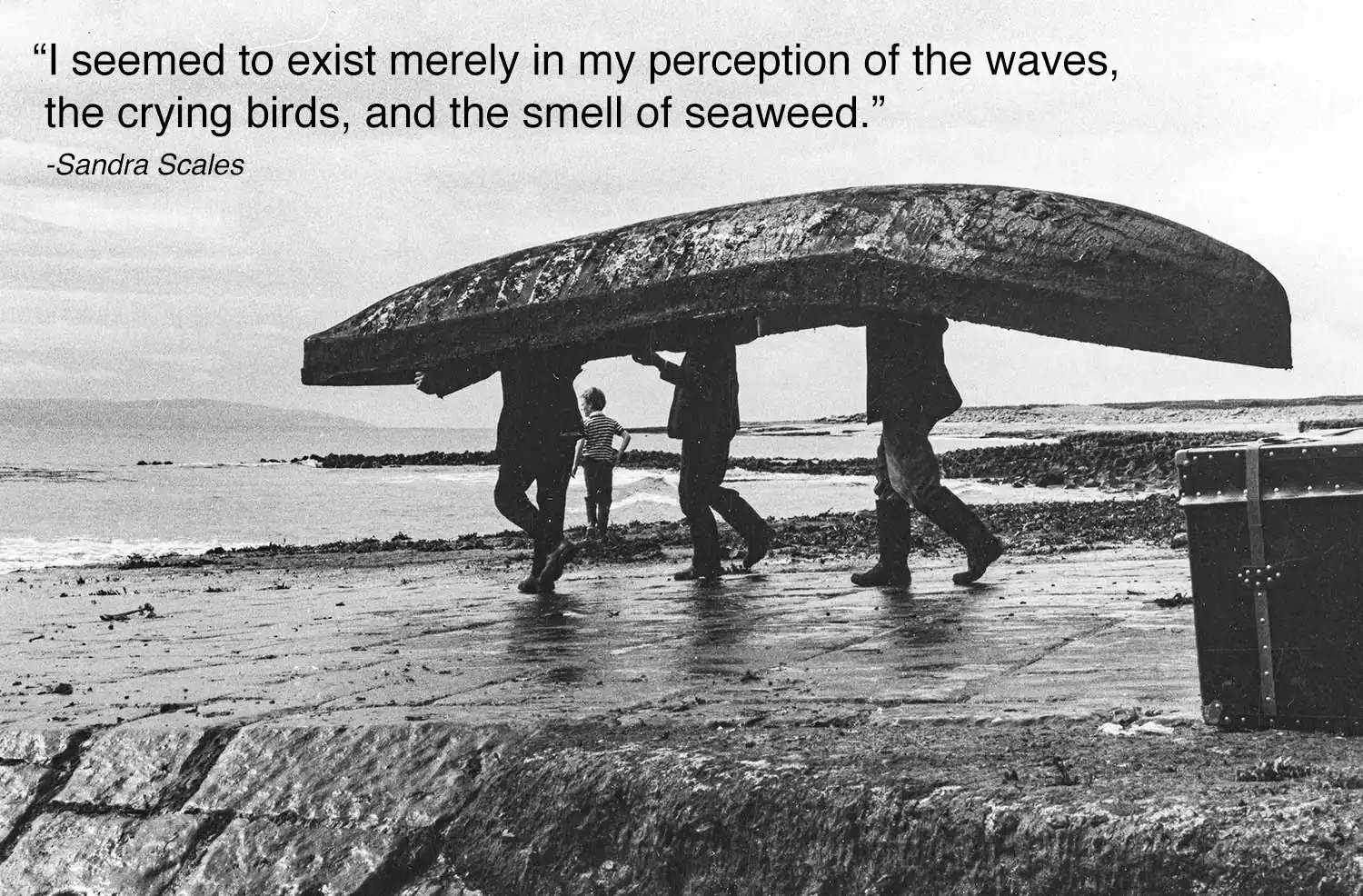 Grayscale photo of men carrying a long boat over their heads inscribed with 'I seemed to exist merely in my perception of the waves, the crying birds,  and the smell of seaweed. -Sandra Scales'