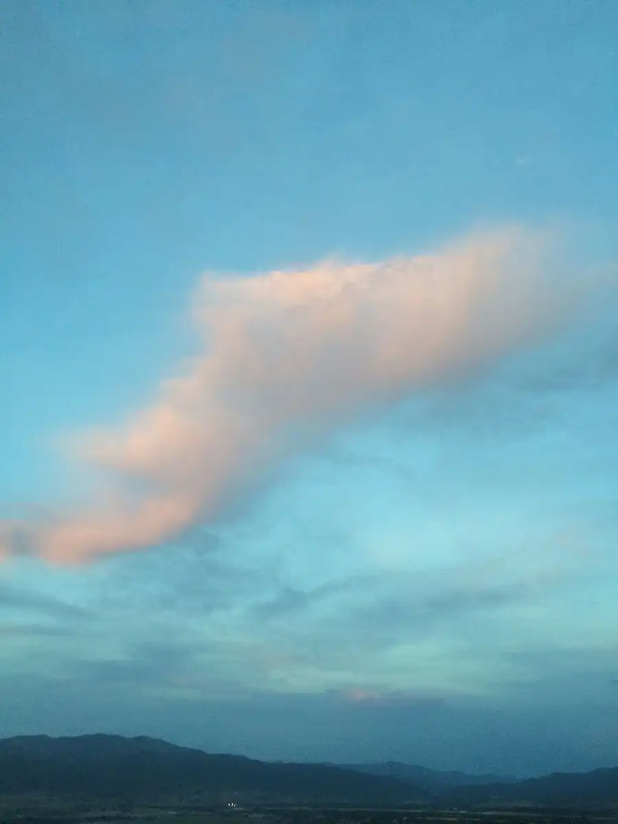 Landscape looking toward mountains with a billowy cloud floating above.